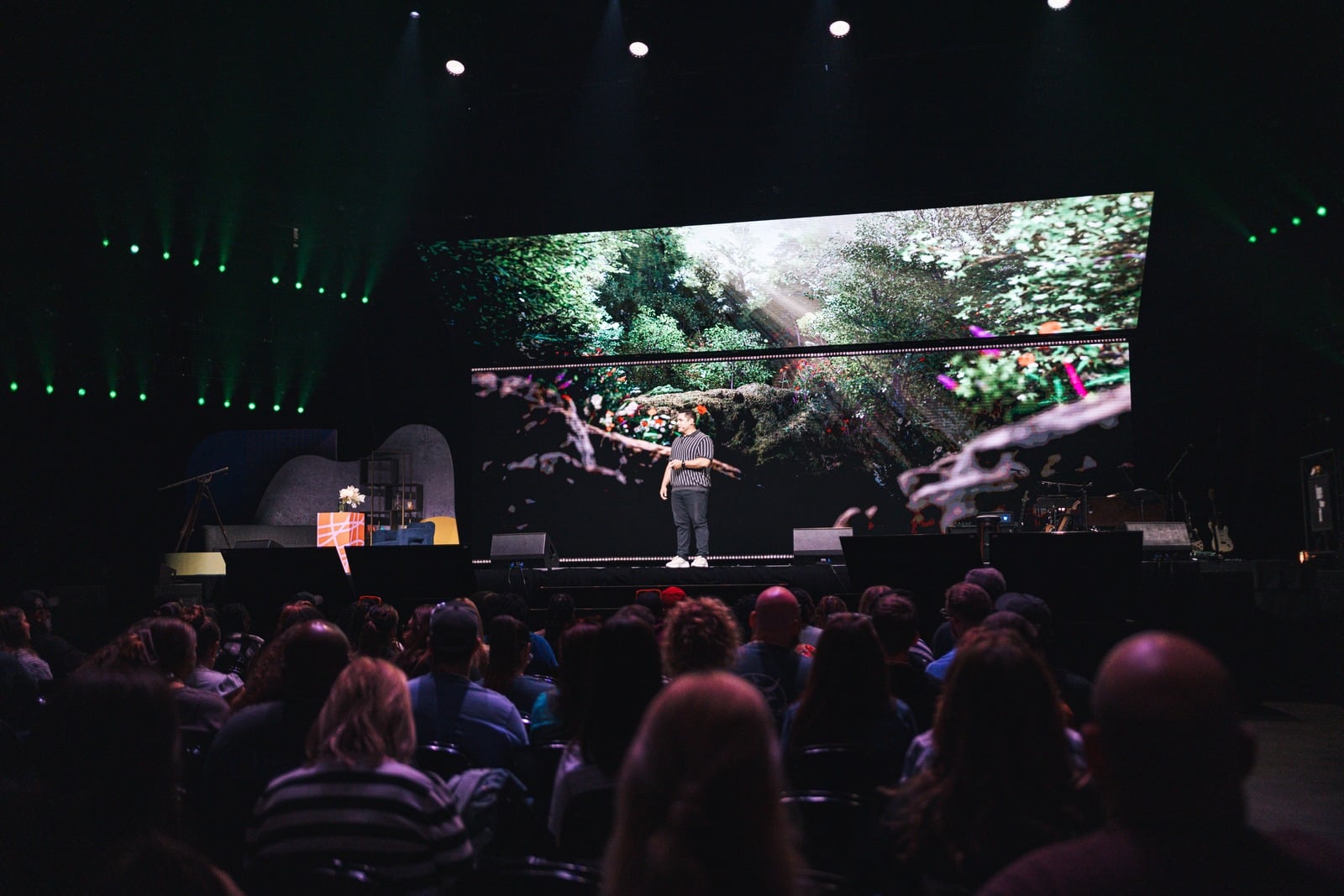 Shane delivering a message on stage to a seated audience